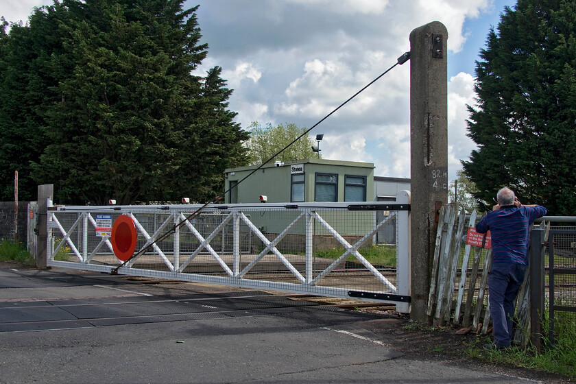 Andy & crossing gates, Stonea 
 With Andy suddenly taking a much deeper interest in railway infrastructure, particularly relating to signalling, I capture him taking a photograph of Stonea's rather anonymous crossing box. This Portakabin replaced a rather nice 1883 Great Eastern box that collapsed into the fen being demolished in 1984. Thankfully the mechanical gates were retained and are still in operation with a very low bridge for smaller vehicles going under the railway. On the day of our visit, we were forced to retrace our steps make a large Fenland detour due to a road closure a short distance south of the level crossing. 
 Keywords: Andy crossing gates Stonea