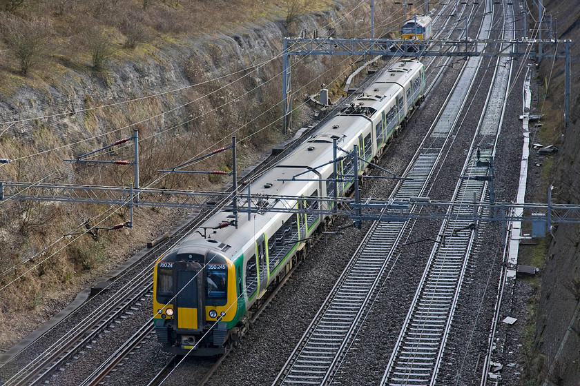 350245, LM unidentified down working & 57302, up LE ex Rugby, Roade cutting 
 As 57302 'Chad Varah' heads south through Roade cutting, London Midland's 350245 heads north with an unidentified service. After what had seemed like days of rain with associated flooding around the country it was good to see a little brightness! 
 Keywords: 350245 unidentified down working 57302 Rugby, Roade cutting Chad Varah London Midland Desiro