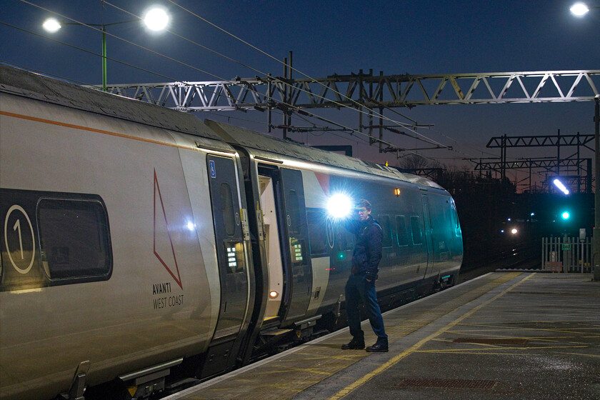 390050, VT 05.42 Wolverhampton-London Euston (1R05, 20L), Milton Keynes Central station 
 The 05.42 Wolverhampton to Euston train has the green light and the feather and is ready to depart with the guard waiting for the dispatchers to give him the nod. This is the early morning and very cold scene at Milton Keynes with Pendolino 390050 about to depart as a Class 350 Desiro can be seen approaching on the down slow line. Notice the first signs of daylight in the distance with the rising sun just colouring the early morning sky. 
 Keywords: 390050 05.42 Wolverhampton-London Euston 1R05 Milton Keynes Central station Avanti West Coast Pendolino