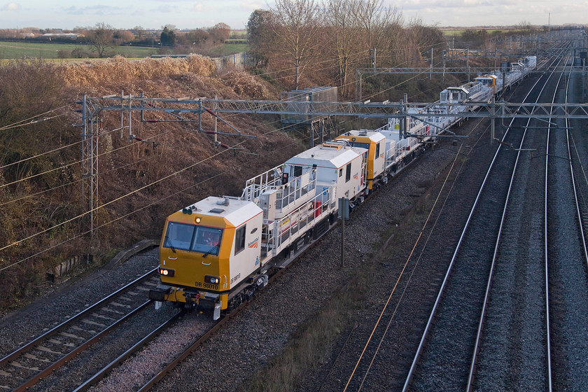 DR98010, DR98011, DR98004 & DR98003, 11.58 Chelmsford-Rugby, Victoria bridge 
 I had been tracking this working on Opentraintimes presuming that it was some kind of infrastructure train and I was correct. DR9810, DR98011, DR98004 and DR98003 form the 11.58 Chelmsford to Rugby move past Victoria bridge in south Northamptonshire. These Network Rail operated multi-purpose vehicles are used in connection with repairs and maintenance of the OLE. The centre sections between the two cabs are platforms that raise up enabling staff to undertake work at height. 
 Keywords: DR98010 DR98011 DR98004 DR98003 11.58 Chelmsford-Rugby Victoria bridge