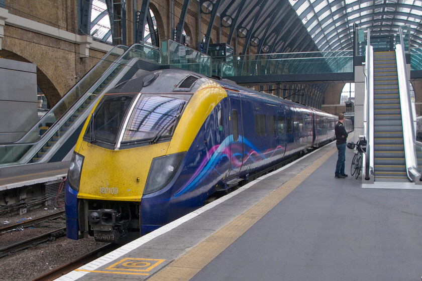 180109, HT 09.48 London King's Cross-Hull (1H01), London King's Cross station 
 One of the fourteen un-loved Adelante Class 180s stands on the blocks at King's Cross. 180109 wears its First Group livery and will soon work the 09.48 service to Hull for Hull Trains. I hope that the customer with the bike waiting patiently on the platform has booked a space for his bike as space is extremely limited on modern trains for cycle storage; a shocking situation that needs to be addressed. 
 Keywords: 180109 09.48 London King's Cross-Hull 1H01 London King's Cross station Hull Trains