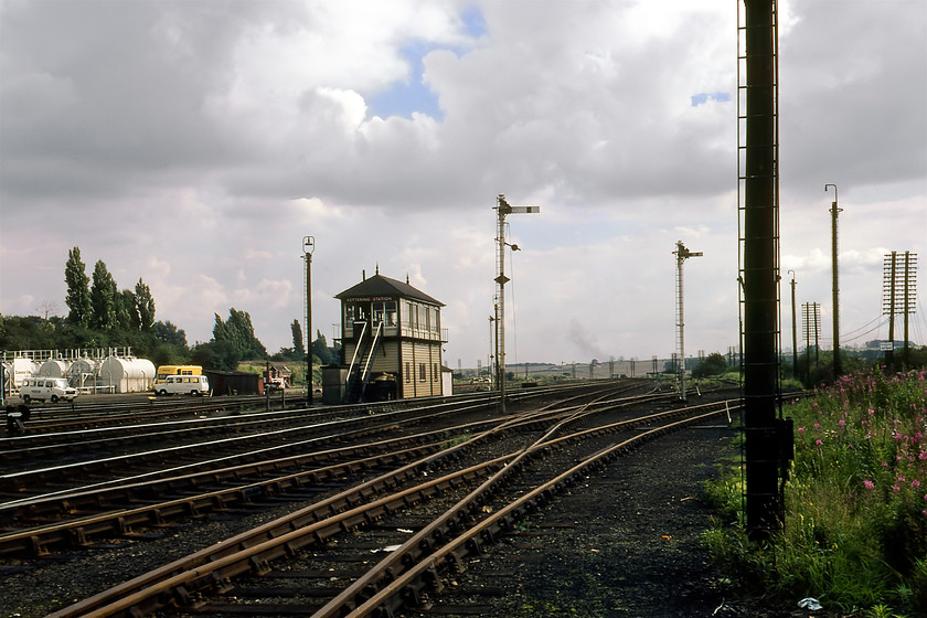 Kettering Station signal box (Mid, 1913) & curve to Cransley 
 Graham and I had must have simply wandered off the end of the station ramp at Kettering to take this photograph....could you imagine the fuss that this would cause today with all trains between St. Pancras and Derby stopped no doubt! Back in 1980, there was no such attention paid to us as we took this image of Kettering Station signal box. It's a 1913 Midland box that controlled all movements around Kettering station including its yards, sidings and junctions. This included the line diverging off to the right here that was the freight only branch to Loddington that once served the extensive opencast ironstone workings close to the village. In later years only the shortened spur to Cransley remained synonymous as the location of the Cohen's scrapyard where many steam and first-generation diesel locomotives met their fate. Delivered by rail, these locomotives would have made their last journey down the short spur over the rails directly in the foreground that curve off to the right. The Midland Railway Type 4E signal box still exists having been dismantled and moved to The Midland Railway at Butterly named Swanick Junction. By way of comparison, some thirty-four years later, whilst the scene had changed considerably, the lamp posts still existed, see..... https://www.ontheupfast.com/p/21936chg/29948597604/x2-222020-em-09-29-london-st-pancras 
 Keywords: Kettering Station signal box curve to Cransley