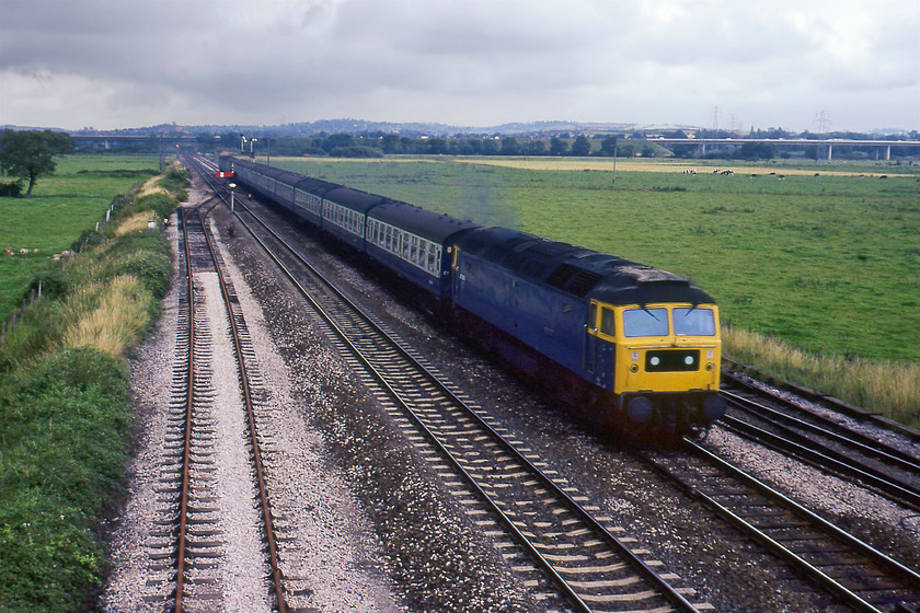 47089, 08.50 Swansea-Paignton (1B80), Exminster 
 47089 'Amazon' gets its head as it passes Exminster with the 1B80 08.50 Swansea to Paignton. This photograph was rescued from the reject's box due to it being too underexposed so I have had to do a fair bit of work to make it presentable. 47089 had another seven years in service until ignominiously meeting its end at Chinley after hitting 31440. Both locomotives were never repaired with Amazon being taken to Cooper's metals at Sheffield for final disposal. Notice the M5 viaduct in the background crossing the Exe estuary.

There is an audio recording of this event on my youtube channel, see....https://youtu.be/Pai0I7YwPXs 
 Keywords: 47089 08.50 Swansea-Paignton 1B80 Exminster Amazon