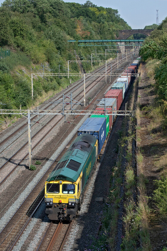 66418, 04.59 Trafford Park-Felixstowe North (terminated at Willesden) (4L41, 104L), Roade cutting 
 With the heat really building 66418 'Patriot - In Memory of Fallen Railway Employees' climbs through Roade cutting leading the very late running 4L41 04.59 Trafford Park to Felixstowe Freightliner. With the temperature already in the mid-thirties, the crew in Class 66s would really be struggling as the cabs have no air conditioning. I suspect that this would be tolerable when the train was in motion but when forced to stop would become extremely uncomfortable. This particular service was probably heat affected as it was already extremely late here at Roade usually passing about before 09.00 (with it now being 10.30) and was terminated on arrival in London at Willesden. 
 Keywords: 66418 04.59 Trafford Park-Felixstowe North terminated at Willesden 4L41 Roade cutting Freightliner