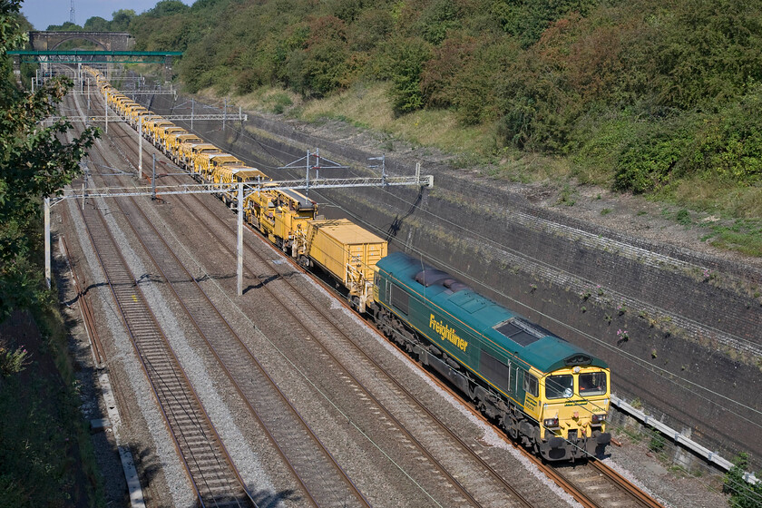 66514, 08.50 Rugby Long Lawford Junction-Willesden HOBC (6Y15), Roade cutting 
 66514 heads the 08.50 Rugby (Long Lawford Junction) to Willesden Junction HOBC jumbo train through Roade cutting. This is an extraordinarily heavy and long train that would normally be far too much for a single Class 66 so another one usually works from the rear. However, on this particular occasion, 66563 still out of sight at the rear was turned off leaving 66514 doing all the work. It was almost at a walking pace here at Roade cutting at the top of an almost constant 1:200 climb from Northampton, a distance of some four miles. 
 Keywords: 66514 08.50 Rugby Long Lawford Junction-Willesden HBOC 6Y15 Roade cutting Freightliner