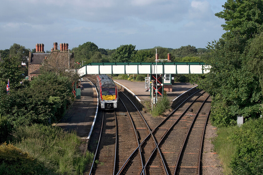 175003, AW 07.34 Manchester Airport-Llandudno (1D34, 4L), Lower Rake Lane Helsby 
 175003 pauses at Helsby station with the 07.34 Manchester Airport to Llandudno TfW service. This photograph, taken from lower Rake Lane, shows the junction to the immediate east of the station with the Ellesmere Port line off to the right. Until relatively recently, this line was a passenger route and, technically, still is but with a bus now replacing rail services serving Ince & Elton, Stanlow and Ellsmere Port stations. As part of the Liverpool City Region Combined Authority Long Term Rail Strategy document of October 2017, it is stated that by 2020 Merseyrail battery (hybrid) trains should be terminating at Helsby as an expansion of the Wirral Line. It's now 2022 and with their new trains not even in service yet I fear that this remains an ambition aim and is still a fair way off! 
 Keywords: 175003 07.34 Manchester Airport-Llandudno 1D34 Lower Rake Lane Helsby TfW Transport for Wales