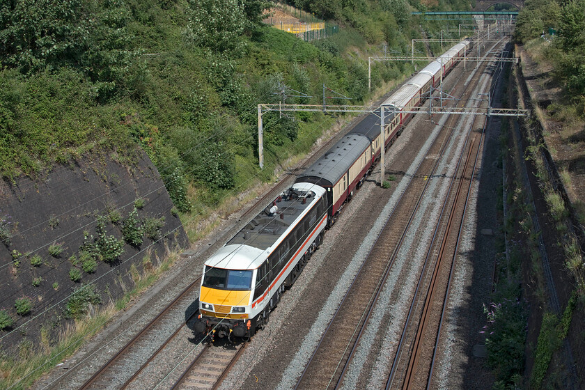 90002 & 47501, 19.23 Dumfries-London Euston (1Z39, 12E), Roade cutting 
 Making a superb sight as it passes through Roade cutting at a reduced speed imposed due to the extremely high temperatures, 90002 'Wolf of Badenoch' leads the 1Z39 19.23 Dumfries to London Euston. Despite this move being well trailed on the various internet posting sites I have been unable to find out what the nature of the train actually was; advice appreciated! The Intercity liveried Class 90 took over the train from Crewe with 47501 'Craftsman' on the rear for the duration. 
 Keywords: 90002 47501, 19.23 Dumfries-London Euston 1Z39 Roade cutting Intercity Swallow Wolf of Badenoch Craftsman