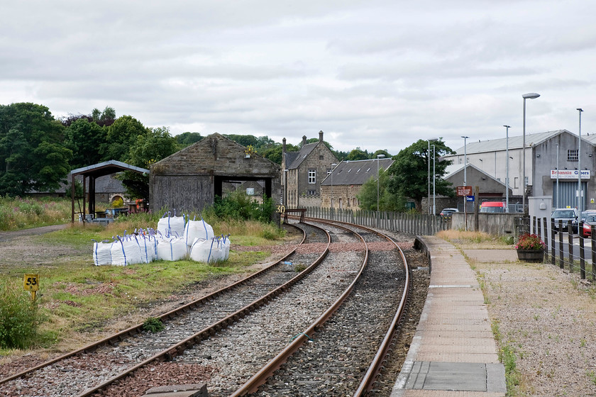 Former branch & goods shed, Keith station 
 The former platform one at Keith Junction (now just Keith) station is seen looking south-west. The two tracks remaining are connected to the Aberdeen to Inverness line and see occasional turnback use, indeed, the track nearest to the platform had recently been used as it was reasonably shiny. Just around the curve in the trees, two-track panels have been removed to disconnect Network Rail from the Keith and Dufftown heritage line that continues onwards. They hope to reinstate the two panels and extend running into platform one again making it the northern terminus of their operations. Notice the granite built goods shed constructed by the Great North of Scotland Railway. 
 Keywords: Former branch goods shed Keith station