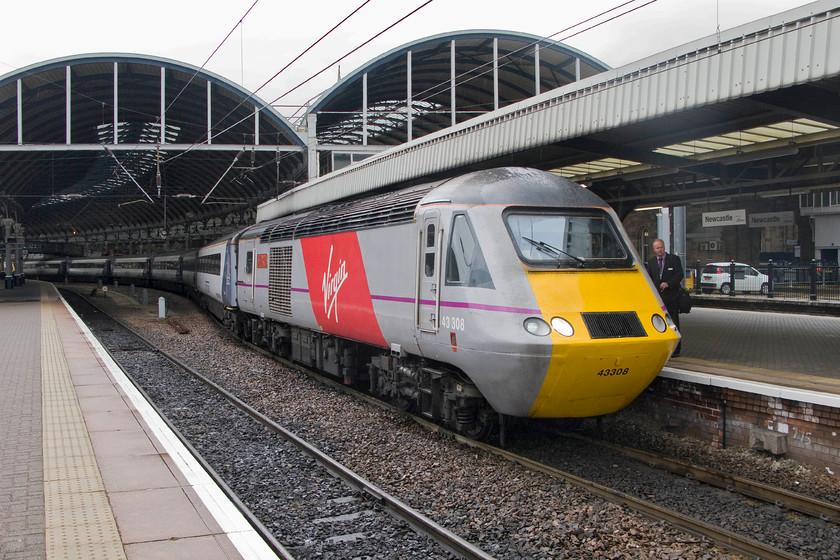 43308, VTEC 11.00 London King`s Cross-Inverness (1S13), Newcastle station 
 A crew change is taking place at Newcastle station as the 11.00 King's Cross to Inverness service pauses on its long journey to Scotland. The leading power car is 43308 'Highland Chieftain' that has had its red vinyl applied by its new operator, Virgin Trains East Coast, who took over operations on the ECML on the first day of last month. The white car in the background is parked on the site of the former suburban platforms that were closed in 1980 when the Newcastle Metro was opened. 
 Keywords: 43308 11.00 London King`s Cross-Inverness 1S13 Newcastle station hst Virgin Trains East coast Highland Chieftain