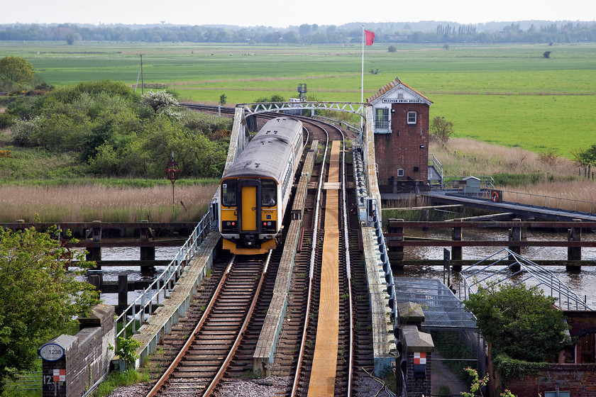 153322 & 153314, LE 15.50 Norwich-Lowestoft (2J82, 12L), Reedham 
 The red flag above the GER 1904 signal/swing bridge box flutters in the easterly breeze as 153322 and 155314 clatter over the River Yare. The two single-car units are forming the 15.50 Norwich to Lowestoft working. When the re-siganalling of the Wherry Lines is completed in spring 2019 this box is to remain for the foreseeable future as Network Rail have found no technological solution to automating the swing bridge; sometimes the old methods just work best! 
 Keywords: 153322 153314 2J82 Reedham swing bridge