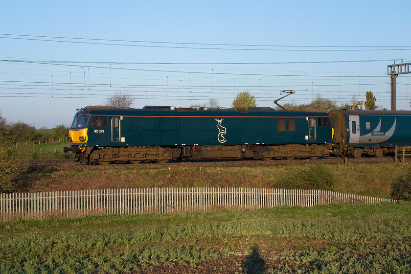 92023, CS 20.45 Inverness, 20.26 Aberdeen, 19.50 Fort William-London Euston (1M16, 10E), between Roade & Ashton 
 For once running to time, the up Caledonian Highland Sleeper passes cold frosty fields between Roade and Ashton just forty minutes from its destination. Notice the shadow of me in the rather poor field of oil seed rape in the foreground created by the very low sun that has just risen above the horizon behind me. 
 Keywords: 92023 20.45 Inverness 20.26 Aberdeen 19.50 Fort William-London Euston 1M16 between Roade & Ashton Caledonian Sleeper