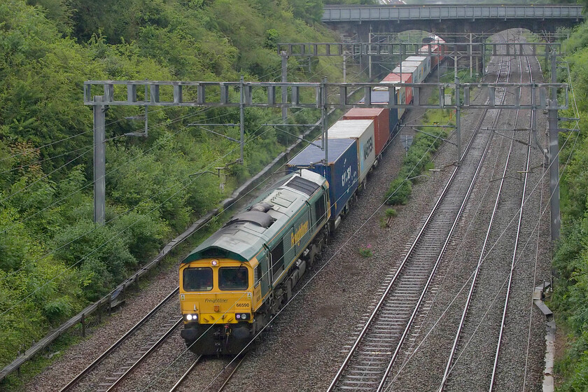 66590, 13.13 Felixstowe North-Lawley Street (4M93, 24L), Hyde Road bridge 
 Just as the tail of the steam-hauled 5Z42 passes under the A508 road bridge in Roade 66590 enters the cutting leading the 13.13 Felixstowe to Lawley Street 4M93 Freightliner almost spoiling the party. By now it was raining pretty heavily and with no protection I was pleased to get on my bike and get home for a welcome cup of tea and dinner but there was one more train to wait for! 
 Keywords: 66590 13.13 Felixstowe North-Lawley Street 4M93 Hyde Road bridge Freightliner