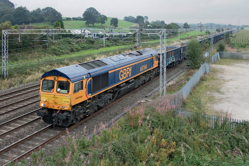 66766, 09.52 Small Heath-Hindlow (4H61, 37L), Stableford bridge 
 Another rake of JNA wagons heads towards their destination to be filled with tons of stone. In this case, passing Stableford led by a smart-looking 66766 it is the 4H61 09.52 Small Heath to Hindlow quarry located just south of Buxton high in the Peak District. 
 Keywords: 66766 09.52 Small Heath-Hindlow 4H61 Stableford bridge GBRf