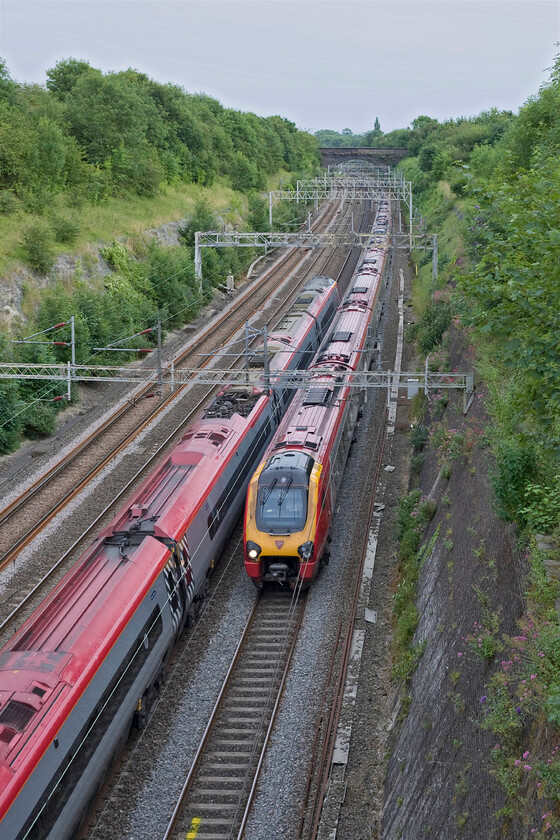 390006, VT 17.15 Manchester Piccadilly-London Euston (1A59) & Class 221, VT 18.03 London Euston-Birmingham New Street, Roade cutting 
 A passing of Virgin services takes place in Roade cutting. To the left Pendolino 390006 speeds southwards with the 17.15 Manchester Piccadilly to Euston. To the right, an unidentified Class 221 works the 18.03 Euston to Birmingham service. Quite why an electric Pendolino could not be found to work this service I do not know. 
 Keywords: 390006 17.15 Manchester Piccadilly-London Euston 1A59 Class 221 18.03 London Euston-Birmingham New Street Roade cutting Virgin Pendolino Voyager