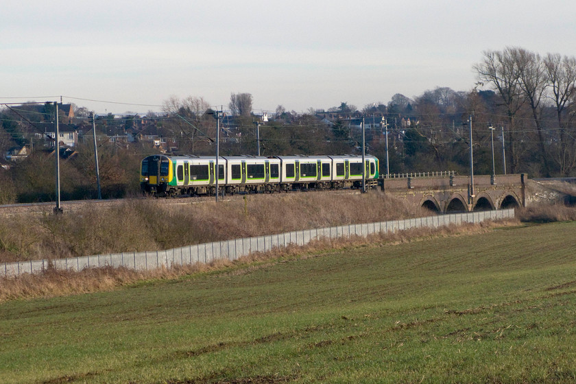 350232, LM 14.25 Northampton-Birmingham New Street (2Y19), Wilson`s crossing 
 Having just crossed a small river on the four arch viaduct in Kingsthorpe meadows to the north of Northampton, 350232 picks up speed with the 14.25 Northampton to Birmingham New Street stopper service. There are discussions under way to develop the field in the foreground, and a number of others behind me, and cover them with a mass of new housing. 
 Keywords: 350232 14.25 Northampton-Birmingham New Street 2Y19 Wilson`s crossing