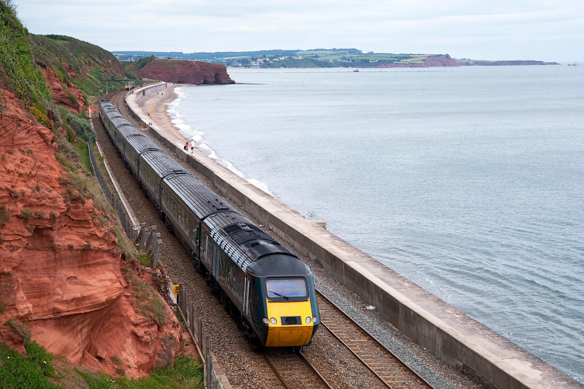 Class 43, GW 13.03 Penzance-London Paddington (1A89, 40L), Dawlish SX971773 
 An unidentified HST in Great Western's new green livery makes its way along the sea wall just east of Dawlish. Much in evidence in the foreground and on the far side of the Exe Estuary is the famous Devon red sandstone dating from the permain period (approximately 298.9 million years). I have found that over the years, the condition of the light turns this to a bright red, to a soft orange even a slightly grey colour. 
 Keywords: Class 43 1A89 Dawlish SX971773