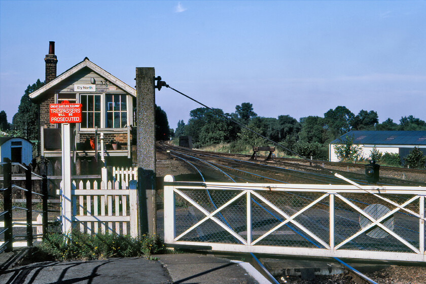 Ely North signal box (GE, 1880) 
 Not to be confused with Ely North Junction, Ely North (often referred to as Ely Station North) controlled the signalling as well as the level crossing at the northern end of the station. Like North Junction, North also controlled some early colour lights using a type of Westinghouse power frame (more information appreciated). In this view, the manual crossing gates are seen that were operated by a gate lad during day shifts with the signalman having to undertake the extra job at night. The crossing was for vehicles over 9 7 that could not use the notorious and tight underpass that caught many a driver out becoming the network's second most common for bridge strikes. The superb box is a Great Eastern Type 2 dating from 1880. Not long after this photograph was taken the manual gates were replaced by barriers with the box eventually shutting in 1992. Notice the recently painted Great Eastern cast sign in the foreground contrasting with the BR corporate identity sign on the box. 
 Keywords: Ely North signal box GE Great Eastern Railway