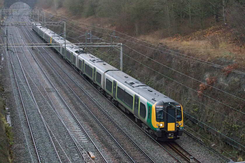 350266, LN 10.33 Birmingham New Street-London Euston (1W10, 5L), Hyde Road bridge 
 360266 and a classmate work the 1W10 10.33 Birmingham New Street to Euston service through Roade cutting on a ridiculously dull December day! The train is just about to emerge from the southern end of the cutting taken from Roade's Hyde Road bridge. The photograph needed a fair amount of Photoshop treatment to deal with the rather strong levels of digital noise caused by the camera utilising an ISO of 10000, a figure unheard of some years ago! 
 Keywords: 350266 10.33 Birmingham New Street-London Euston 1W10 Hyde Road bridge London Northwestern Railway