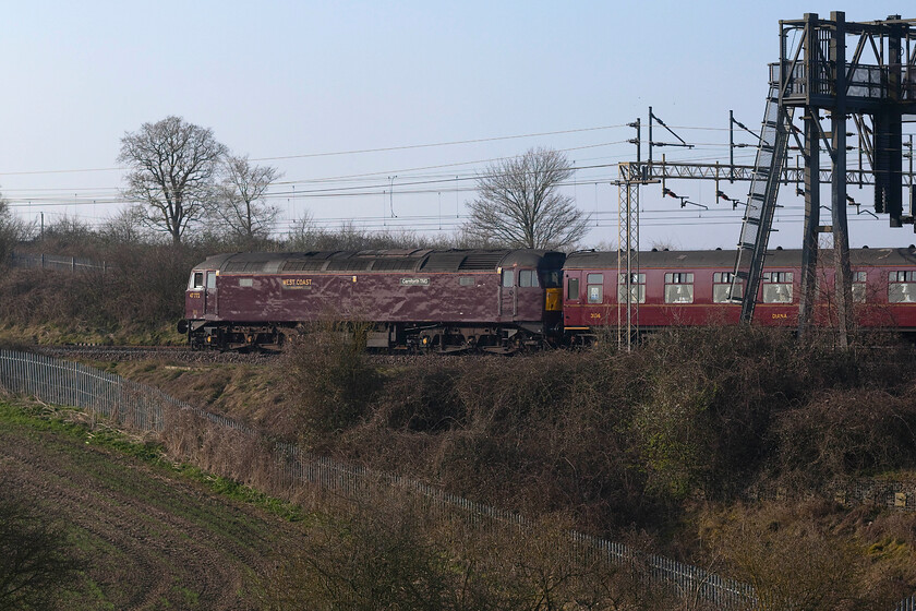 47772 , outward leg of The Mancunian, 06.37 London Euston-Manchester Piccadilly (1Z71, RT), between Roade & Ashton 
 Bringing up the rear of the outward leg of The Mancunian charter from Euston to Piccadilly 47772 'Carnforth TMD' is seen wearing its dreary West Coast livery that still looks dull on such a bright spring morning! Out of sight at the front 6233 'Duchess of Sutherland' made a much finer sight! Notice the droplight of the rear cab is lowered with a relief driver sitting in the seat reading his paper; I've always thought that what a pleasant way it must be to earn a crust sitting at the rear of a train watching the journey pass you by in reverse! 
 Keywords: 4777 The Mancunian 06.37 London Euston-Manchester Piccadilly 1Z71 between Roade & Ashton Carnforth TMD