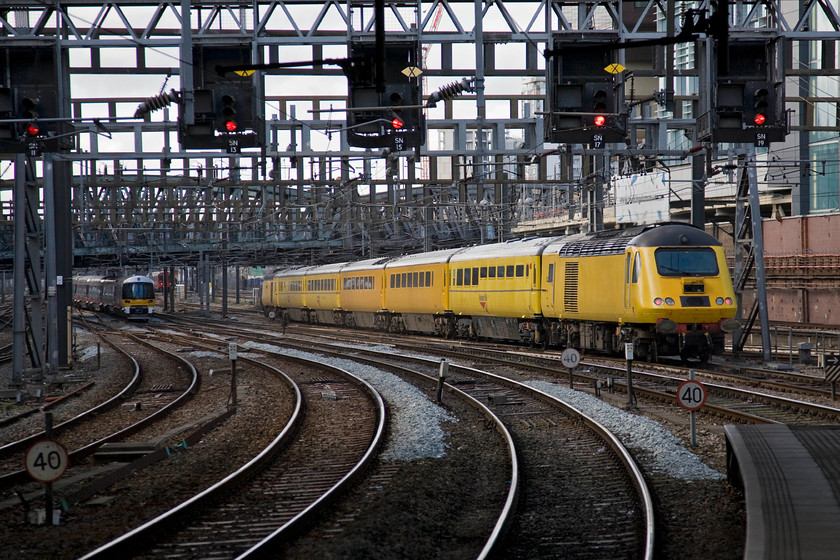 43014 & 43062, 13.29 London Paddington-Derby RTC NMT (1Q21) & Class 332, HX 13.35 London Paddington-Heathrow (1T57), London Paddington station 
 Just twelve minutes after it arrived as the 1Q20 from Exeter Riverside the NMT gets away from Paddington as the 1Q21 13.29 to Derby RTC via Oxford, Banbury, Coventry, Nuneaton (reversal) and Leicester. The bright yellow test train has five Mk. III coaches packed with various measuring and monitoring equipment with 43014 at the rear with 43062 'John Armitt' leading. As it leaves an unidentified Heathrow Express Class 332 is also leaving with the 13.35 to Heathrow Terminal four. 
 Keywords: 43014 43062 13.29 London Paddington-Derby RTC NMT 1Q21 Class 332 13.35 London Paddington-Heathrow 1T57 London Paddington Station Flying banana HST Class 43 Heathrow Express John Armitt