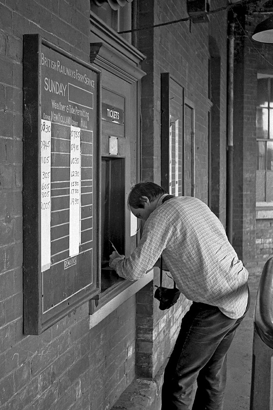 Purchasing tickets, New Holland Pier 
 Graham purchases a single ticket for the car and the two of us to cross the Humber estuary on the MV Farringford. He is at the ticket office on New Holland Town station with a timetable of crossings to his left on the notice board. Also, notice that Graham is doing something that very few of us do these days and that is writing a cheque! He has his trusty Pentax ME (non-Super model) around his neck that I believe he still uses to this day? 
 Keywords: Purchasing tickets New Holland Pier Sealink