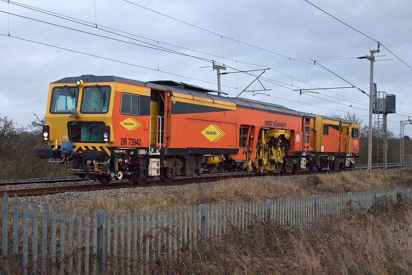 DR73942, 14.14 Hemel Hempsted Boxmoor-Preston Dock Street (69E), Wilson's Crossing 
 Again, as per the earlier DRS light engine move, this 14.14 Hemel Hempsted tamper move was making rapid progress largely due to the many cancelled passenger services resulting from COVID-19 staff absence and another haemorrhaging of passenger numbers. Colas operated Plasser and Theurer 08-4x4/4S-RT Tamper climbs away from Northampton at Wilson's Crossing. I suspect that the driver was delighted that his progress remained so good arriving over an hour early at Preston meaning that he could get home and spend the last evening of the year in some form of celebration. 
 Keywords: DR73942 14.14 Hemel Hempsted Boxmoor-Preston Dock Street 69E Wilson's Crossing Colas Rail Plasser and Theurer 08-4x4/4S-RT Tamper DR73942