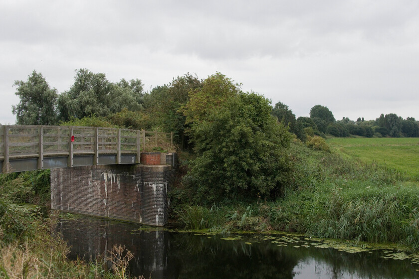 Site of Twenty Feet River signal box 
 I stood in a very similar spot in the summer of 1981looking in the same direction towards March's vast Whitemoor Yard. Then the original bridge spanned Twenty Feet River carrying the double track GN & GE Joint line between March and Spalding that was to close a year later. In the centre distance was Twenty Feet River signal box sitting on the embankment. It was a modern box opened in 1974 replacing the older GE Twenty Feet Siding box that was collapsing into the fenland soil. The newer box only had a working life of eight years being closed when the Joint line was shut in 1982. It did stand boarded up for several years after closure looking particularly sad in a pretty desolate Fenland landscape! 
 Keywords: Site of Twenty Feet River signal box