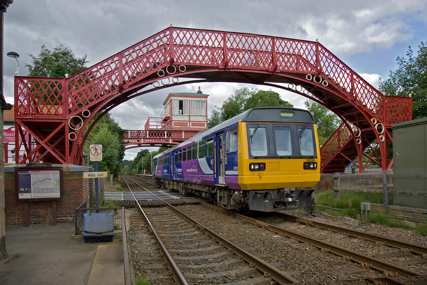 142086, NT 10.45 Hexham-Nunthorpe (2N18), Wylam station 
 Two Grade II listed structures for the price of one! Both the footbridge and the 1897 North Eastern Railway signal box seen here are both on Historic Englands register so their future is secure even when the semaphores on this line are replaced in the not too distant future. I suspect that the Pacer in the form of 142086 working the 10.45 Hexham to Newcastle service will not be recorded by them when it to is declared surplus to requirements in the next two or three years! 
 Keywords: 142086 10.45 Hexham-Nunthorpe 2N18 Wylam station Northern Trains Pacer