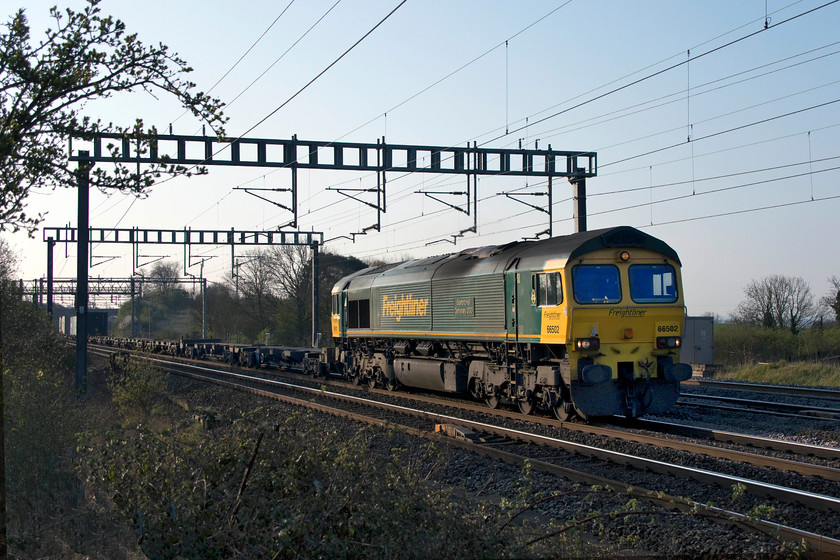 66502, 04.25 Felixstowe North-Lawley Street (4M88), Ashton Road bridge 
 66502 'Basford Hall Centenary 2001' passes between Roade and Ashton on the southern WCML with the 4M88 04.25 Felixstowe to Lawley Street FReightliner working. There are a number of Freightliner flats behind the locomotive that have no boxes, this train is more commonly heavily loaded than this. Despite it being mid-April and with clear blue skies, it was a bitterly cold morning with a raw easterly breeze. 
 Keywords: 66502 04.25 Felixstowe North-Lawley Street 4M88 Ashton Road bridge