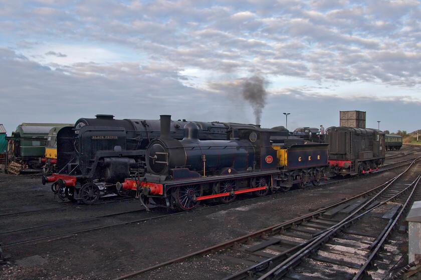 92220, 564 & 12131, stabled, Weybourne Yard 
 Weybourne Yard is always packed with stock and a vast range of locomotives. In this late afternoon view Worsdell former GER 564 that is a regular performer on the NNR. Somewhat dwarfing the 0-6-0 is the familiar bulk of the late David Shepherd's 9F 92220 'Black Prince'. Class 11 shunter number 12131 dating from 1952 completes the lineup with a whisp of smoke emanating from the funnel of 7F 53809 in the background. 
 Keywords: 92220 564 12131 Weybourne Yard Black Prince GER