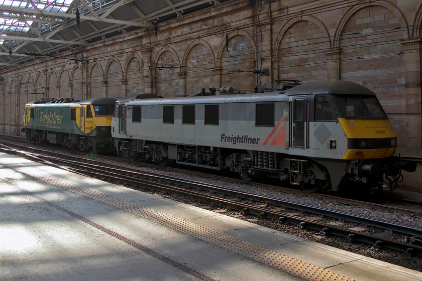 90043 & 90047, stabled, Edinburgh Waverley station 
 Two Freightliner class 90s rest at Edinburgh Waverley station in two different liveries. 90043 is in their newer green and yellow livery whilst 90047 is in the their rather dated grey scheme. These two locomotives are 20% of Freightliner's fleet of class 90s that were introduced on the network in 1990 making the earliest example nearly thirty years old! 
 Keywords: 90043 90047 stabled, Edinburgh Waverley station