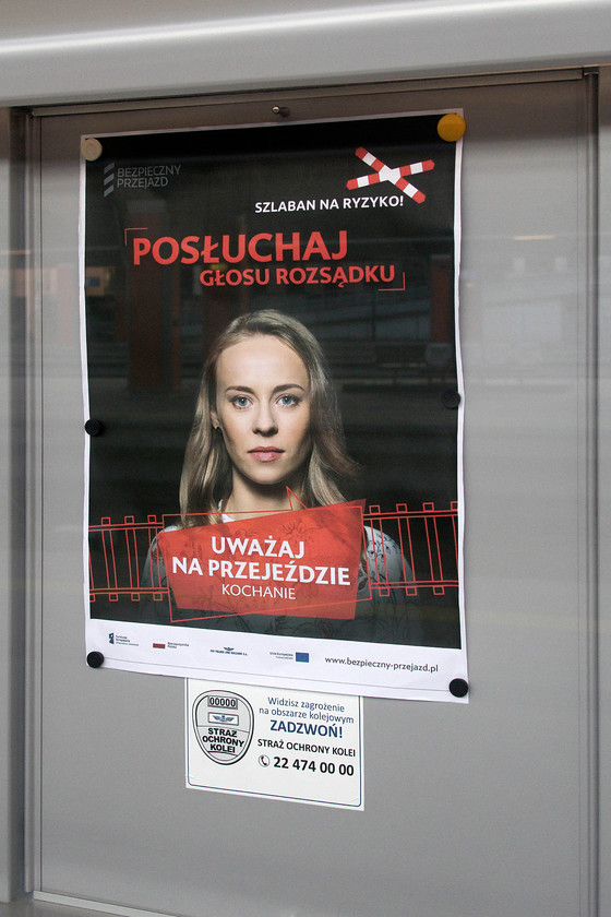 Safety poster, Krakw-Glwny station 
 I saw a number of these posters around Krakw Glwny station and even without doing any translation I think that I understood the message! The railways in Poland seemed to be typically open as in much of mainland Europe with a lack of fencing and random crossing points that were not signed. Despite this, PKP seems to be promoting safety on level crossings under the title of 'safe crossing'. Google Translate did a reasonable job in identifying the wording but it was as to be expected with the girl voicing the message, 'Think on Crossing Sweetheart' and the mantra 'Listen, Voice, Reason' written above her image. Also notice at the bottom of the poster that the EU has promoted this campaign as well as PKP and the Polish regional government. 
 Keywords: Safety poster Krakw-Glwny station {PKP Polish Railways