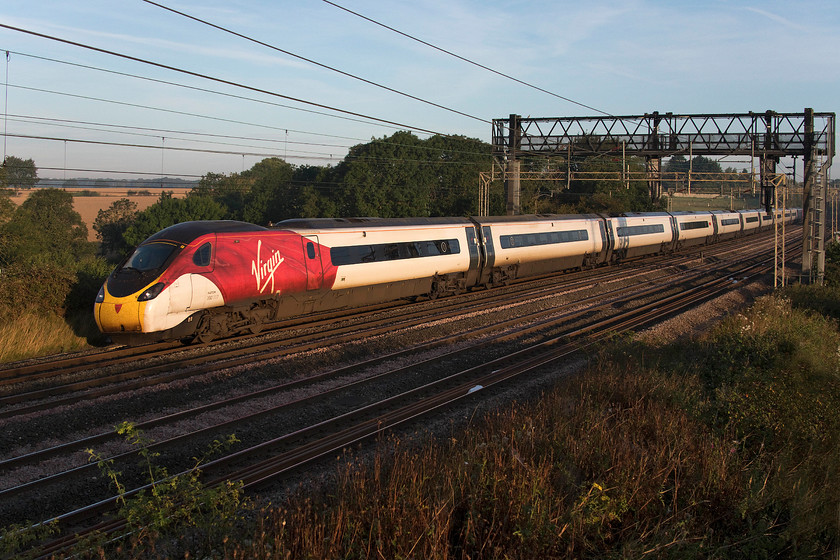 390117, VT 06.15 London Euston-Manchester Piccadilly (1H61, RT), Roade Hill 
 In the early morning sun, 390117 'Blue Peter' heads north between Roade and Ashton on the southern WCML forming the 06.15 Euston to Manchester Piccadilly. I love being out on the lineside in the early morning before everybody else is about and as for the quality of light, that is something else! In this picture, the golden fields of wheat are seen in the background awaiting their day of fate with the combine harvester. 
 Keywords: 390117 06.15 London Euston-Manchester Piccadilly 1H61 Roade Hill