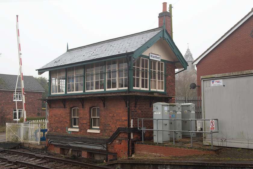 Wainfleet Signal Box (GN, 1889) 
 Wainfleet All Saints, to give it its full name, is situated some six miles from Skegness and has a population of just under 2 000. The railway arrived in 1873 and the signal box, seen here, in 1889 both being constructed by the Great Northern Railway. This box is a much simpler design of their standard boxes and of the rest found on the Poacher Line as it's known. It is seen in the mist here with All Saints Parish Church in the background. 
 Keywords: Wainfleet Signal Box GN, 1889