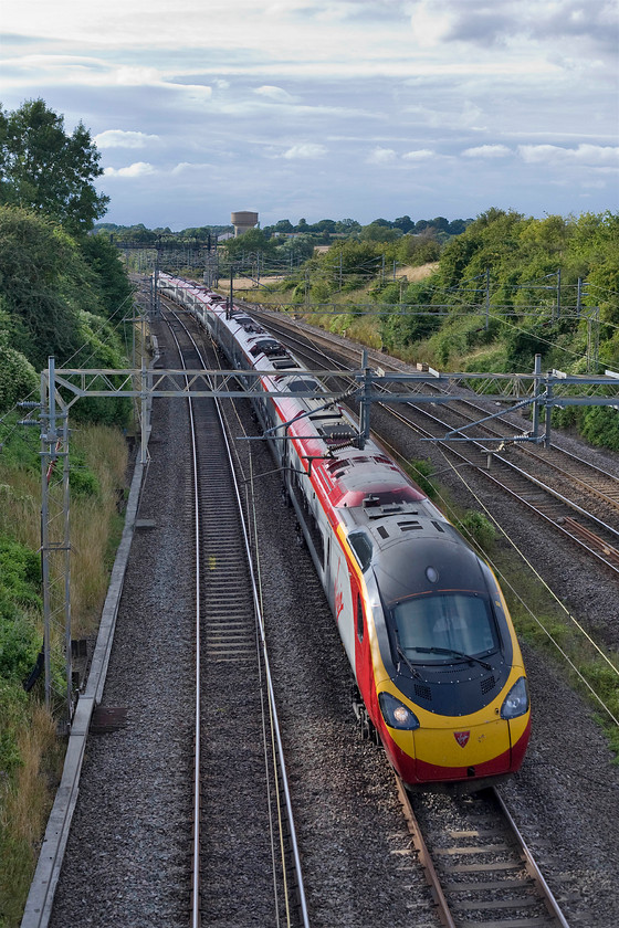 390125, VT unidentified up working, Victoria bridge 
 I give up! Despite all the technology available today I cannot identify this Virgin Trains up working seen passing Victoria bridge in Northamptonshire. With the summer sunshine catching one of Roade's two water towers, this one on Ashton Road, 390125 heads south on the up fast. 
 Keywords: 390125 unidentified up working Victoria bridge 390125, VT unidentified up working, Victoria bridge Virgin Trains Pendolino