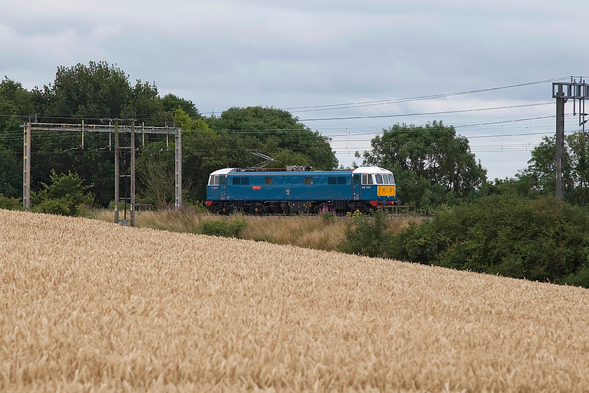 86259, 12.22 London Euston-Rugby LE (0Z89), Roade Hill 
 86259 'Peter Pan/Les Ross' runs along the down slow past Roade Hill in Northamptonshire with the 12.22 Euston to Rugby Carriage Sidings LE move as 0Z89. Having worked the return Cumbrain Mountain Express the previous day, it makes this short move to the rather overgrown sidings just north of the line at Rugby where it sits all week awaiting its next call. Given it does this, it's all the more surprising that its paintwork still looks so fresh. 
 Keywords: 86259 12.22 London Euston-Rugby LE 0Z89 Roade Hill