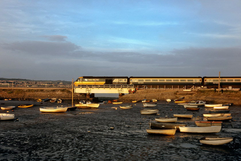 Class 43, 18.40 Plymouth-London Paddington, Cockwood Harbour 
 A classic location and a classic train! An unidentified HST power car and set passes Cockwood Harbour with the 18.40 Plymouth to London Paddington train. Unfortunately, even a close examination of the power car does not reveal its number. However, it does reveal the family by the bridge who are fitting themselves up with buoyancy aids that seems odd as the tide is well and truly out making any sailing activities tricky! 
 Keywords: Class 43 18.40 Plymouth-London Paddington Cockwood Harbour HST