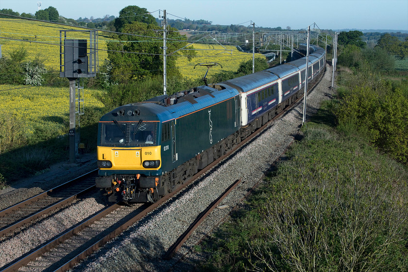 92010, CS 19.50 Fort William, 21.43 Aberdeen, 20.45 Inverness-London Euston (1M16, RT), Milton crossing 
 Doing its best to camouflage itself, 92010 leads the up 'Highland' sleeper past Milton crossing between Blisworth and Roade on the southern WCML. By this stage, Caledonian Sleeper had introduced the new Mk. V sleeper stock to its 'Lowland' service that passes this spot about an earlier before this one. Within a month the plan is to withdraw the thirty-year-old Mk. III stock as seen here with the transformation to the new stock then complete. 
 Keywords: 92010 19.50 Fort William 21.43 Aberdeen 20.45 Inverness-London Euston 1M16 Milton crossing