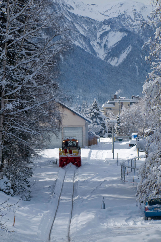 Snowblower, Chamonix Mt 
 Against a dramatic Alpine scene, one of the line's one-metre gauge snowblowers has just emerged from the shed at back and the SNCF member of staff is preparing it for work. 
 Keywords: Snowblower Chamonix Mt. Blanc yard