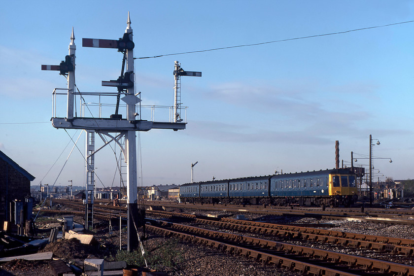 Class 127 DMU, 14.35 London St. Pancras-Bedford, Cricklewood junction 
 Despite appearances there is actually two signal brackets in this image with them blending seamlessly into one. In the foreground is a superbly antiquated wooden Midland bracket that contains the home for the line curving away to the left round to Dudding Hill junction. It also has a shunting signal and a calling-on arm. Behind the wooden structure is a steel more modern affair with just one dol on it that has the home for trains coming away from Dudding Hill. 
 Keywords: Class 127 DMU, 14.35 London St. Pancras-Bedford, Cricklewood junction