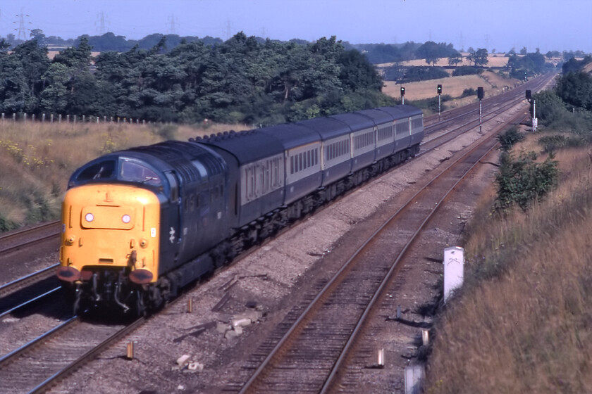 55007, 08.07 York-London King's Cross (1A08), Essendine TF043129 
 Utilising my 135mm telephoto lens fitted to my Pentax ME Super 55007 Pinza is seen tearing down Stoke bank approaching Essendine leading the 1A08 08.07 York to Kings Cross service. The train is composed of air-braked ETH stock with a BG marshalled, as usual, at the front. It is the wide open unbroken views of the ECML in locations such as this that I remember so fondly; its not the same today with the wires in place, palisade fencing and the smart-looking but, rather dull, Azumas passing this same spot but you cannot prevent progress I suppose! 
 Keywords: 55007 08.07 York-London King's Cross 1A08 Essendine TF043129 Pinza