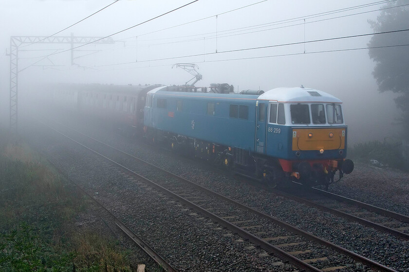 86259, outward leg of The Cumbrian Coast Express, 07.10 London Euston-Carlisle (1Z86, 6L), Milton Crossing 
 86259 'Les Ross/Peter Pan' heads north through the thick September fog working the outward leg of The Cumbrian Coast Express. Running as is usual as 1Z86 the train left Euston at 07.10 terminating at Carlisle. Here, steam would then lead the charter around the glorious Cumbrian Coast route to Lancaster. 
 Keywords: 86259 outward leg of The Cumbrian Coast Express 1Z86 Milton Crossing Les Ross Peter Pan