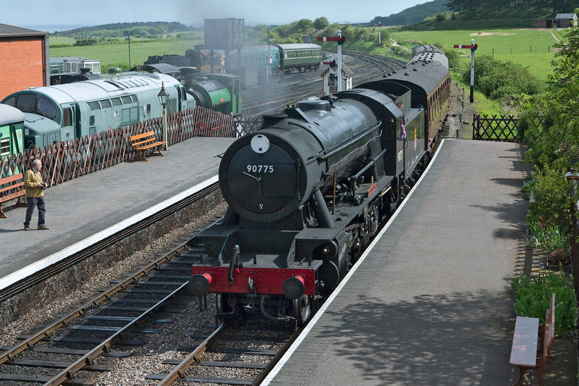 90775, 10.30 Sheringham-Holt, Weybourne station 
 Having driven across to Norfolk, our first stop was at the Poppy Line or the North Norfolk Railway. Here, Andy watches former War Department Austerity 2-10-0 90775 bring the 10.30 Sheringham to Holt into Weybourne station. In the background is the Weybourne yard with various stock in view. 
 Keywords: 90775, 10.30 Sheringham-Holt, Weybourne station