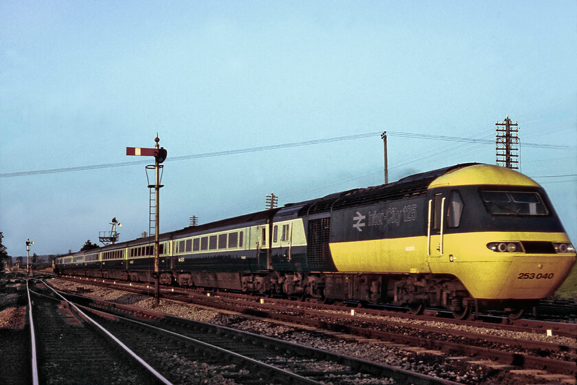 253040 (43150), 18.25 London Paddington-Penzance, Witham 
 Another photograph of an HST at Witham that I also fouled up! Combined with the fact the photograph is also badly afflicted with the Fujichrome hue I also managed to press the shutter a millisecond too late! I have done a fair bit in Photoshop 'adding' some image to the right-hand side in order to just bring the nose cone of W43150 in! HST set 253040 speeds past Witham working the 18.25 Paddington to Penzance service. 
 Keywords: 253040 43150 18.25 London Paddington-Penzance Witham Class 43 HST