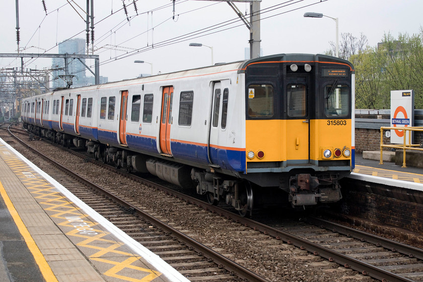 315803, LO 13.03 London Liverpool Street-Chingford (2T56, RT), Bethnal Green station 
 313803 enters Bethan Green station working the 13.03 Liverpool Street to Chingford service. This unit is one of a sub class of seventeen operated by London Overground. All are imminently going to be withdrawn and scrapped having been in-service for very nearly forty years. I wonder if their replacements, the class 710 Aventras, will last as long? 
 Keywords: 315803 13.03 London Liverpool Street-Chingford 2T56 Bethnal Green station