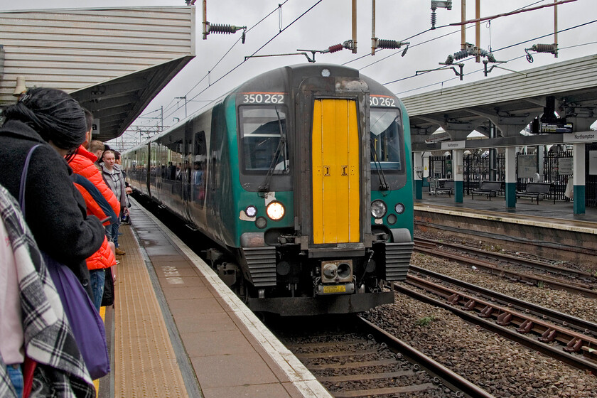 350262, LN 10.10 Northampton-London Euston (2N06, 1E), Northampton station 
 Notice the very crowded platform and a London train starting from Northampton's platform two. After very heavy overnight rain Crick tunnel was flooded so a complete closure of the line north of Northampton to Hillmorton Junction was in place. Prior to busses being arranged all passengers heading north from Northampton were advised to travel south as far as Milton Keynes to then head north via the Weedon line to Rugby and beyond. To complicate matters further the slow lines were closed for engineering works south from Hanslope Junction through and past Milton Keynes. Our train to London arrives from the depot to form the 2N06 10.10 service that should have originated from Birmingham New Street. Whilst the service was understandably initially busy it thinned out after Milton Keynes. 
 Keywords: 350262, LN 10.10 Northampton-London Euston (2N06, 1E), Northampton station London Northwestern Desiro