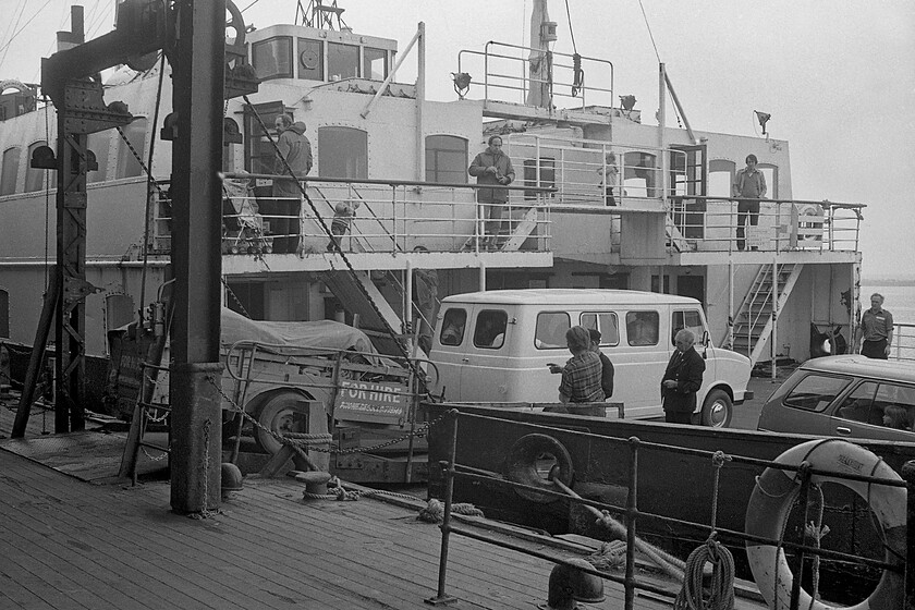 Loading MV Farringford, New Holland Pier 
 A Leyland Sherpa minibus, that looks well loaded with passengers, drives on to the MV Farringford at New Holland Pier ready to make the crossing to Hull Corporation Pier. The crew are in discussions as to how to best deal with the abnormally long load on the ferry deck so as not to block out other drivers. Notice the 'for hire' notice painted in the side and the rear of the trailer. This was in the days before galvanised lightweight modern trailers were available to customers with this one probably based on a former caravan chassis as was the case at the time. 
 Keywords: Loading MV Farringford New Holland Pier Sealink