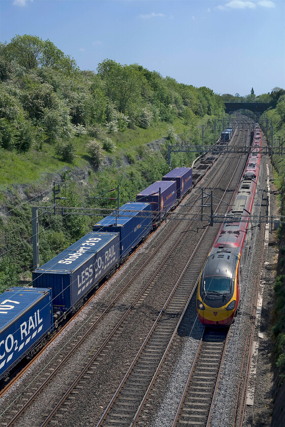 66430, 12.03 DIRFT-Purfleet (4L98), & Class 390, VT 12.37 London Euston-Manchester Piccadilly (1H67), Roade cuttinge 
 Stobart is more associated with their big green lorries rather than with rail. However, since 2006 they have been cutting a furrow on the national network by conveying containers for Tesco with DRS providing the service. One of their regular flows is the 4L98 12.03 (or time thereabouts) from Daventry (DIRFT) to the Purfleet deepwater terminal on the Thames Estuary. It is seen passing through Roade cutting with 66430 leading at the front whilst a Virgin Class 390 speeds north working the 12.37 Euston to Manchester Piccadilly. 
 Keywords: 66430 12.03 DIRFT-Purfleet 4L98 Class 390 12.37 London Euston-Manchester Piccadilly 1H67 Roade cutting Stbart Rail DRS Direct Rail Services Virgin Pendolino