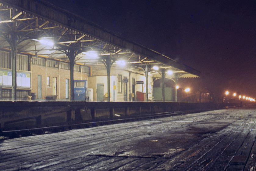 New Holland Pier station 
 A desolate scene on New Holland Pier railway station stuck out in the Humber Estuary and it snowing just to add to the occasion! The station would offer little protection to foot passengers who either walk along the pier to the left under the superb line of LNER globe lamps or whilst waiting for their ferry or train to arrive. Notice the blue battery powered tractor on the platform used for towing various trolleys down the loading ramp to the pontoon to be taken on to MV Farringford. 
 Keywords: New Holland Pier station