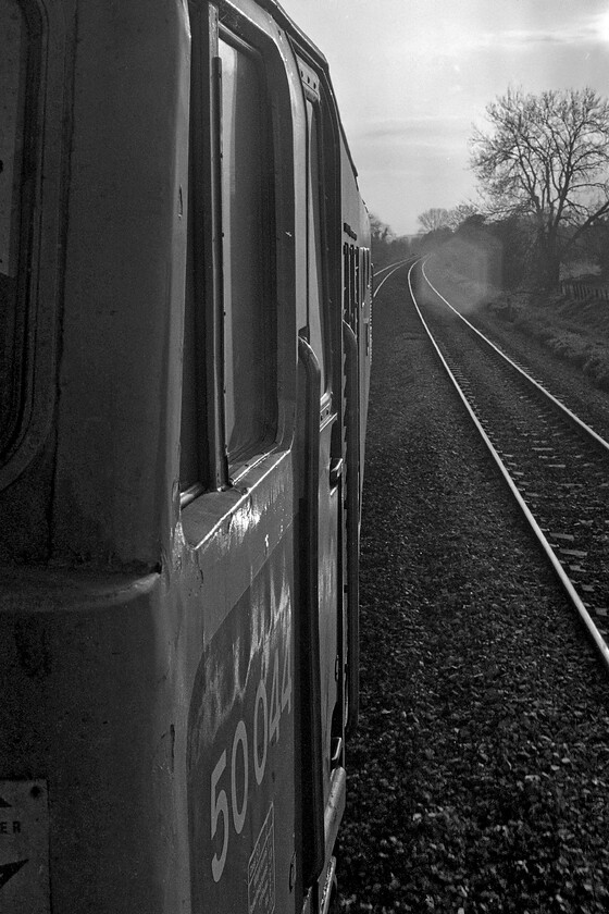 50044, 17.52 London Paddington-Westbury (1K68), nr. Pewsey 
 Taken from the leading droplight of the stock 50044 'Exeter' shatters the Wiltshire peace as it accelerates away from its stop at Pewsey. Our photography group had enjoyed a great day in London at the Photoworld show and an equally enjoyable (well for me the railway enthusiast at least!) journey back on the 1K68 17.52 Paddington to Westbury evening commuter service. I have it in my notes that the driver of the Class 50 was utilising as much of the 2,700 hp as he could really giving it some beans between the frequent stops that this service makes. It has to be remembered that this train was pathed between a number of much faster and non-stopping HSTs so there really was no time to dawdle with no facility to pass trains from Newbury to Westbury but for a loop at Woodborough. 
 Keywords: 50044 17.52 London Paddington-Westbury 1K68 Pewsey Exeter